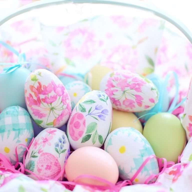 A basket filled with decorated Easter eggs in pastel colours and floral patterns.